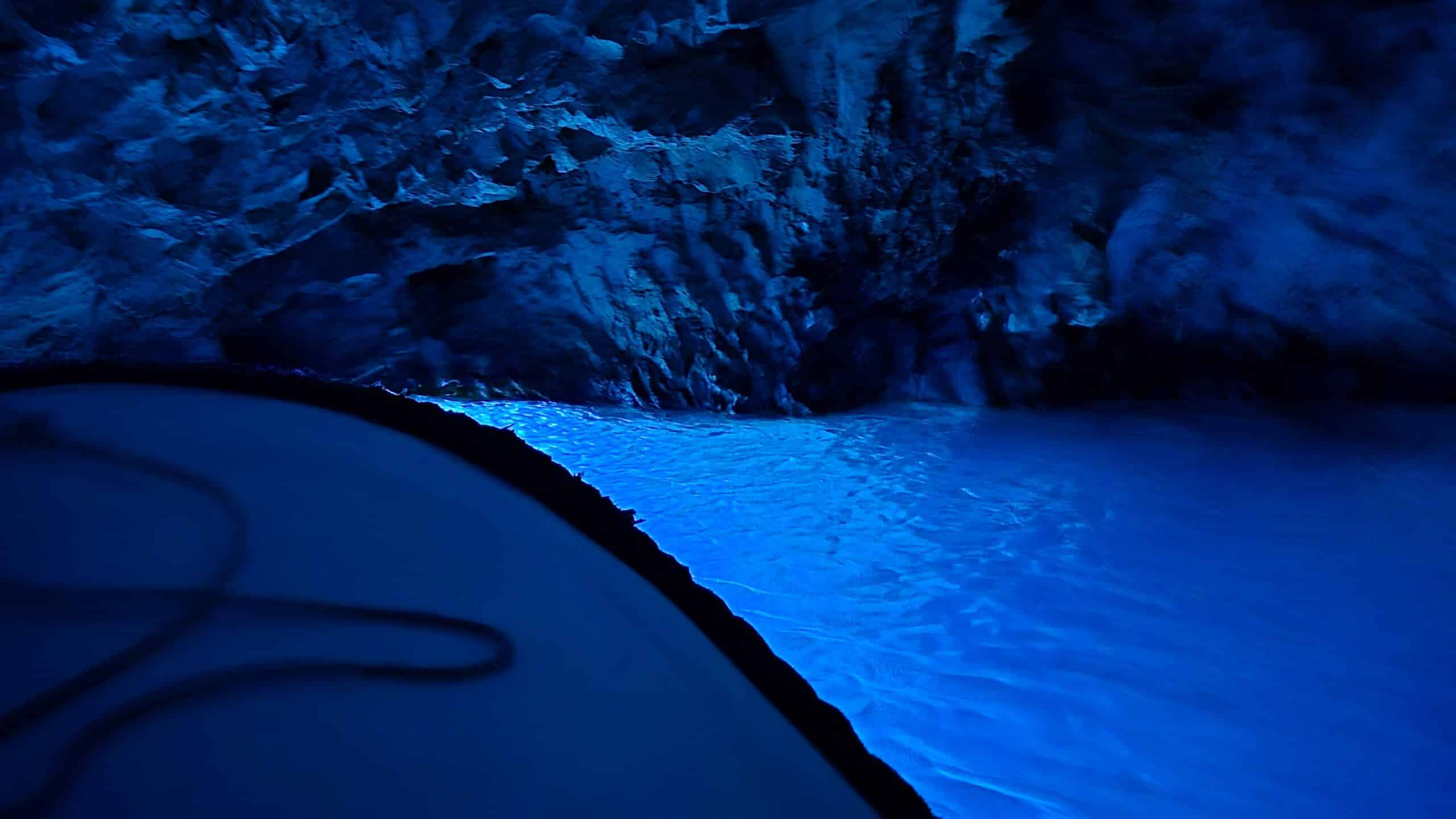 The Blue cave illuminated by blue light, with a body of water inside. Day trip from cruise. 